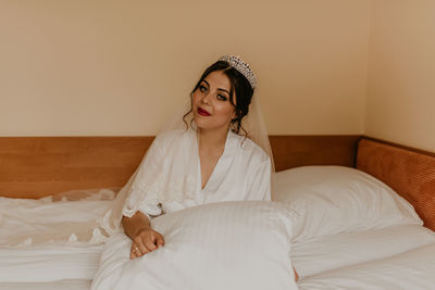 Portrait of young woman lying on bed at home