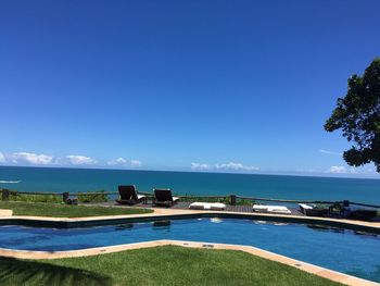 Scenic view of swimming pool by sea against blue sky