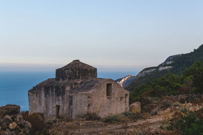 Old building by sea against sky