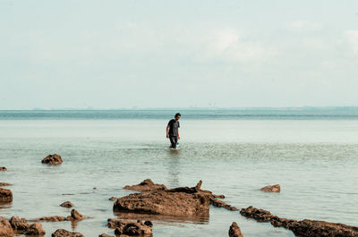 Man walking in the shallow water in beach