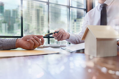 Real estate agent giving pen to client at table in office