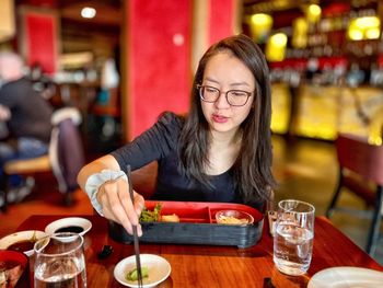 Portrait of asian woman eating japanese meal at table in restaurant.