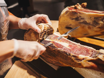 Midsection of butcher cutting meat at store