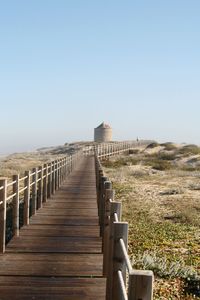Wooden walkway leading towards castle against clear sky