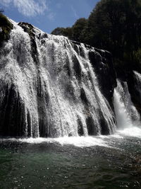 Low angle view of waterfall against sky