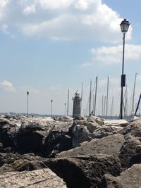 Lighthouse on rock against cloudy sky