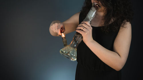 Midsection of woman smoking hookah against white background