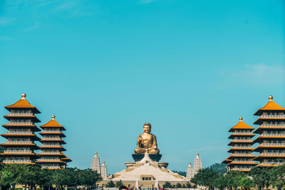 Buddha temple amidst buildings against blue sky