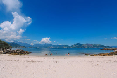 Scenic view of sea by mountain against sky