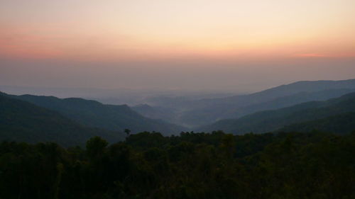 Scenic view of silhouette mountains against orange sky