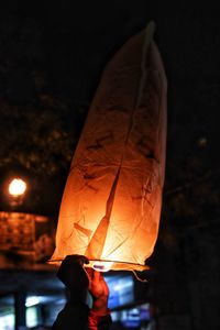 Midsection of person holding illuminated lantern at night