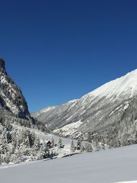 Scenic view of snowcapped mountains against clear blue sky