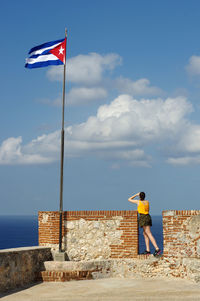 Man standing by flag against sky