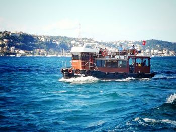 Boat sailing on sea against rocky mountains