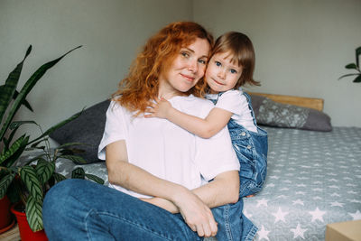 Young mother and child have fun and fool around at home on the bed