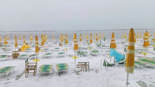 Chairs and tables on beach against sky