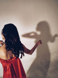 Rear view of woman dancing against shadow on wall