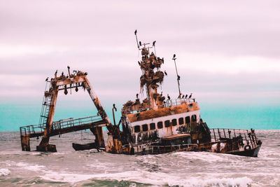 Abandoned ship in sea at sunset