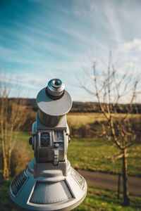 Coin-operated binoculars on field against sky