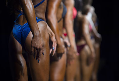 Midsection of female athletes posing against black background
