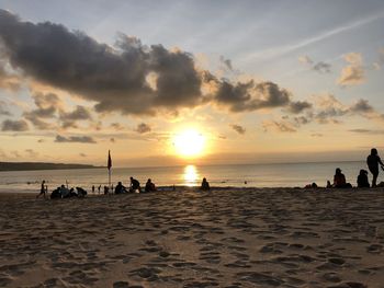 Silhouette people on beach against sky during sunset