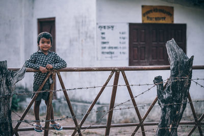 Woman standing by fence against building