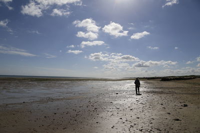 Woman walking on beach against sky