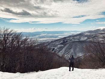 Man standing on snow covered landscape against sky