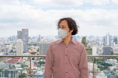 Portrait of man looking at cityscape against sky