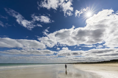 Australia, south australia, robe, summer clouds over silhouette of female tourist walking alone along fox beach