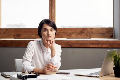 Young woman using mobile phone while sitting on table