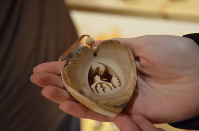 Cropped hands of woman holding carved wooden decoration