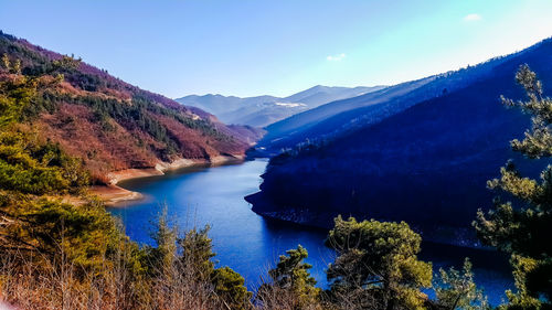 Scenic view of lake and mountains against blue sky