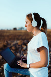 Side view of woman using mobile phone against sky