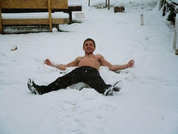 Portrait of shirtless man lying on snow