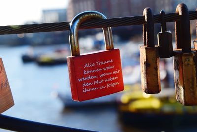 Close-up of padlocks hanging on metal railing at bridge over river