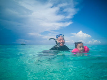 Smiling woman with daughter in sea