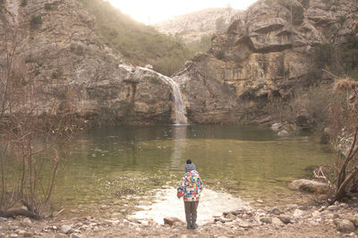 Man standing on rock by lake in forest