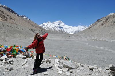 Woman with arms outstretched standing against mt everest