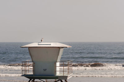 Seagull perching on beach hut against clear sky