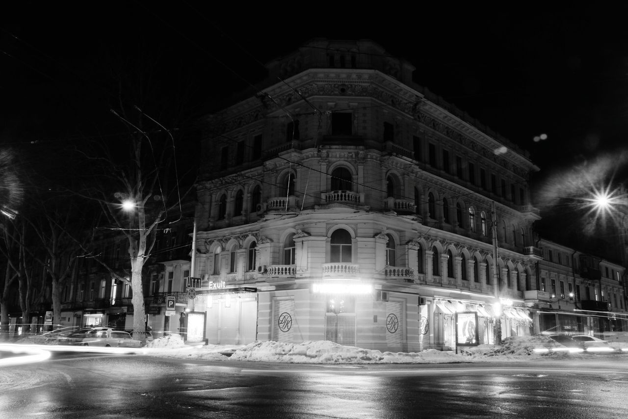 night, illuminated, building exterior, architecture, built structure, street light, street, lighting equipment, city, water, motion, reflection, light - natural phenomenon, outdoors, building, waterfront, incidental people, facade, long exposure, sky