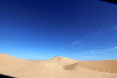 Scenic view of desert against blue sky