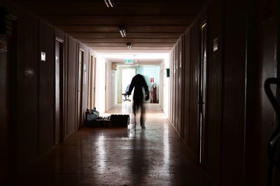 Rear view of man walking in corridor of building