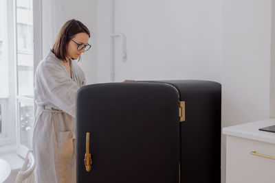 Woman looking inside of refrigerator at home
