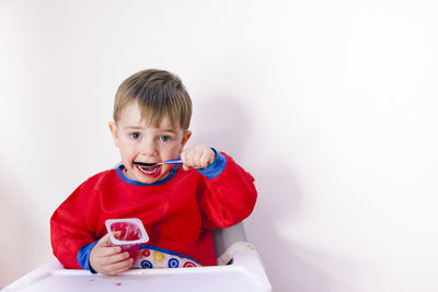 Portrait of cute boy holding toy against white background