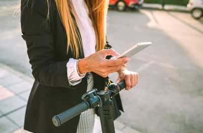 Woman using mobile phone on street in city