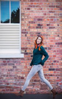 Portrait of young man standing against brick wall