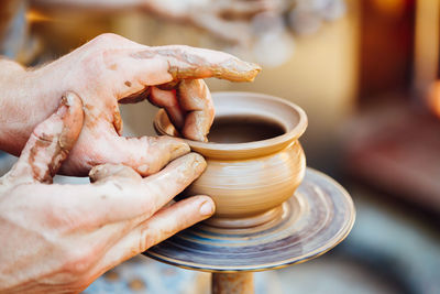 Cropped hands of potter making clay pot at pottery