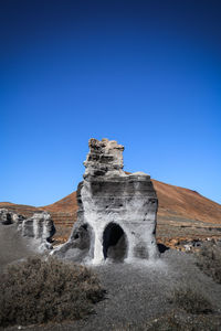 View of rock formations against clear blue sky