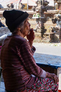 Side view of woman sitting outdoors